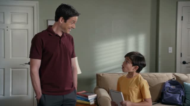 Ace sharing an idea from his notebook with his dad in their living room.